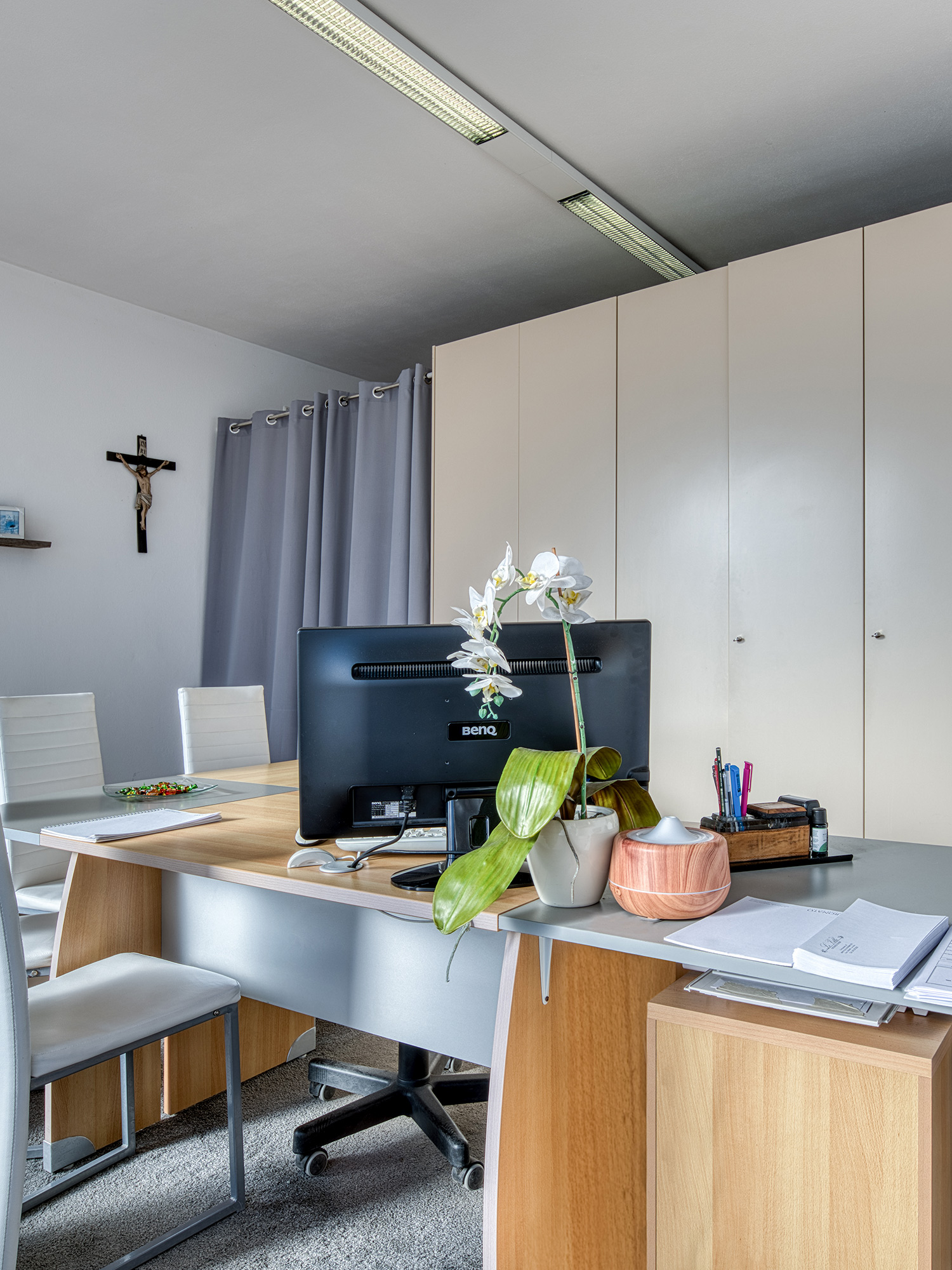 Interno dell'ufficio di un'agenzia funebre con scrivania e crocifisso