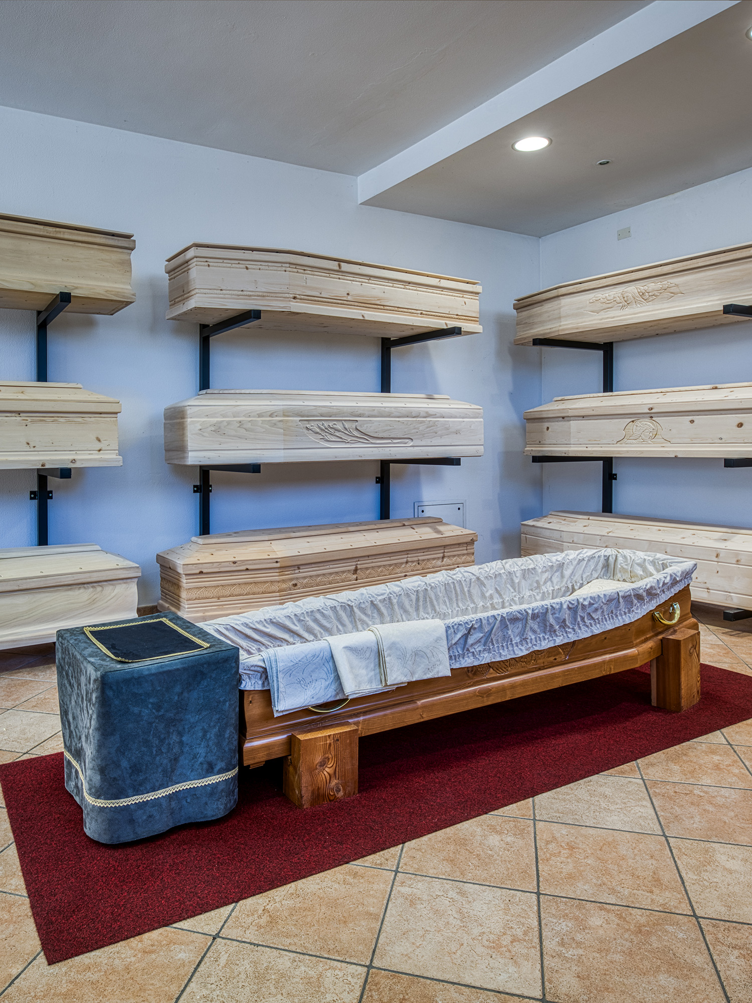 Esposizione di cofani funebri in legno chiaro in una sala dedicata